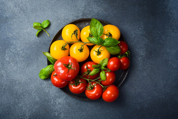 Fresh organic colored tomatoes on a black stone plate. Top view.