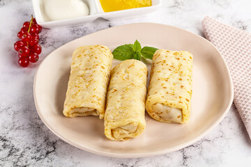 Homemade stuffed pancakes with honey and cream sour
