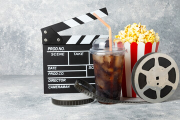 Tasty popcorn in buckets and cold cola drinks with cinema tickets, movie clapper and 3D eyeglasses...