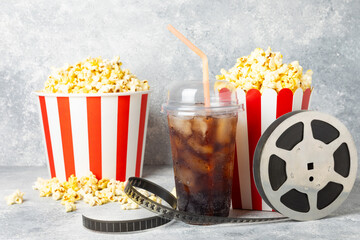 Tasty popcorn in buckets and cold cola drinks with cinema tickets, movie clapper and 3D eyeglasses...