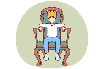 Little boy sits on throne with crown on head dreaming of growing up to be prince or king. Teenager boy in golden crown made of paper laughs with eyes closed and imagining monarchy.