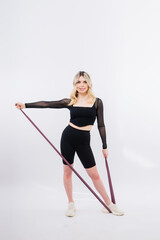 Woman in black sports clothes exercising with resistance band in studio.