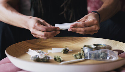 Person, hands and rolling cannabis for blunt in house, weed and prepare joint for smoking. Herbal pharmaceutical, 420 and hallucinogenic in marijuana, holistic and stress relief for mental health
