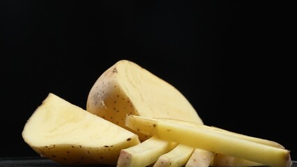Macrography, the essence of sliced potato against a sleek black background takes center stage. Each close-up shot meticulously captures the intricate details and textures of the potato. Comestible.