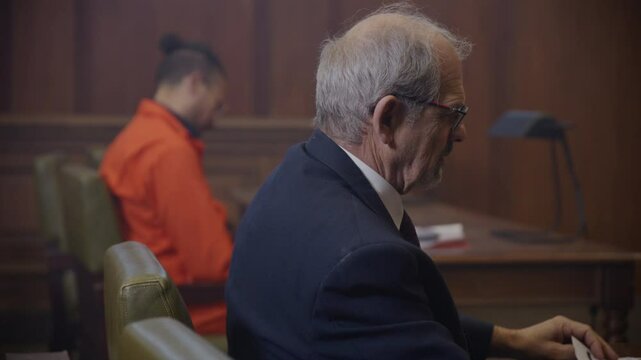 Rack focus from prosecutor to black man in court room trial