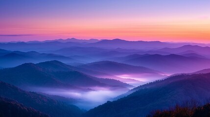 Obraz premium A panoramic view of a mountain range shrouded in mist during a vibrant sunset