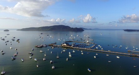 View of a marina with numerous boats and yachts docked, surrounded by calm waters