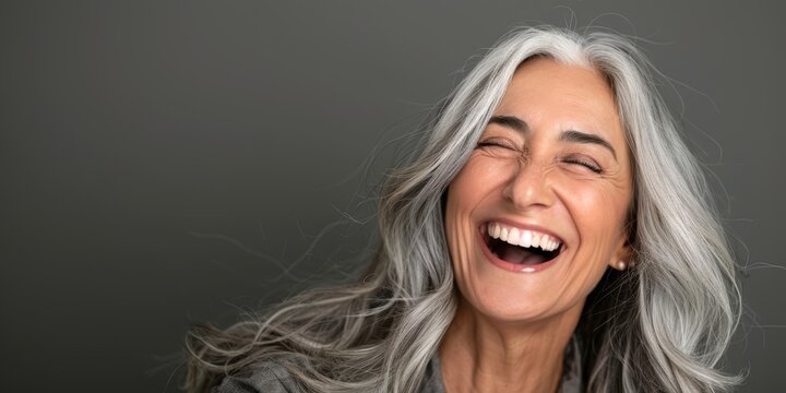 Beautiful gorgeous 50s mid age beautiful elderly senior model woman with grey hair laughing and smiling. Mature old lady close up portrait. Healthy face skin care beauty, skincare cosmetics,