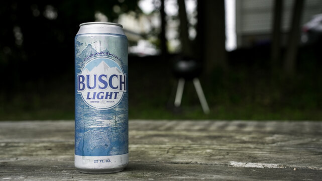 NORWALK, CT, USA - JULY 22, 2024: A can of Busch Light sits on a wooden table in a backyard
