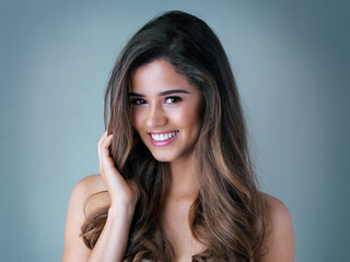 Naklejka premium Hair care, salon and woman in studio with beauty, collagen and volume treatment for confidence. Smile, portrait and female person with brunette, long and shiny hairstyle isolated by gray background.
