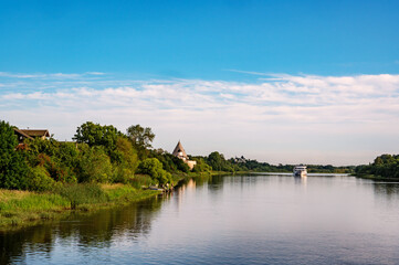 Beautiful morning landscape of the banks of the Volkhov River. In the distance is a cruise ship and a medieval fortress