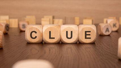 four wooden cubes with the text 'CLUE' on a brown background