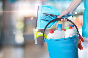 Cleaning woman with cleaning products in bucket.