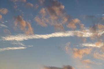 Low and high altitude clouds stacked in the blue evening sky creating color contrast between the orange and white clouds