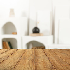 Wooden empty table background in bright cozy modern home interior. Blurred furniture. Copy space for advertising products and objects. Natural daily light.