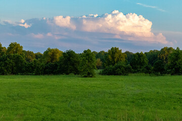 Beautiful cloud formation at sunset over a green field with tree line