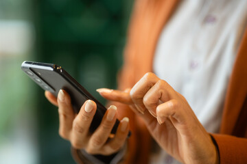 Latin Woman Using Mobile Phone in Cafe. Close-up of Female Hands Typing on Smartphone.
