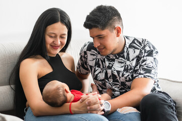 couple of young Latino parents proudly looking at their newborn baby girl