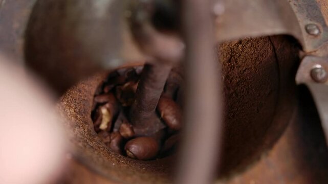 Close up view of the vintage coffee grinder rotating and grinding roasted coffee beans. High quality 4k footage