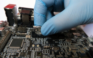 Technician replaces the flat battery on a battery-backed electronic board. 3-Volt lithium coin...