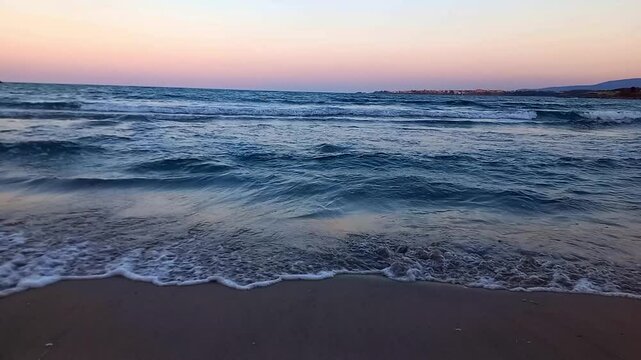 Seascape. Sunset or sunrise on sea in summer. Calm sea, small waves rolling onto sandy shore. Vacations on Black Sea coast in Bulgaria, city of Kiten, South Beach. Summertime.