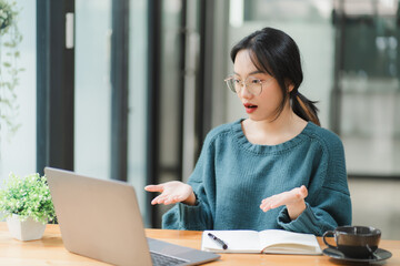 Shocked by the Screen: Young Asian woman, working remotely, reacts with surprise to her laptop,...