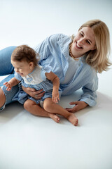 Happy family concept. Beautiful smiling mother embracing her cute little 1 year old girl, looking at camera isolated at studio over white background