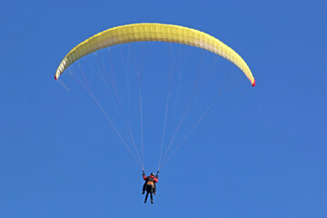 Tandem Paraglider flying in a blue sky