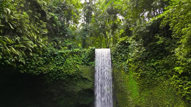 Aerial view of Tibumana waterfall, a beautiful hidden waterfall in rainforest, Bali, Indonesia.  Tibumana Waterfall referred to by locals as Air Terjun Tibumana is one of the most beautiful place.