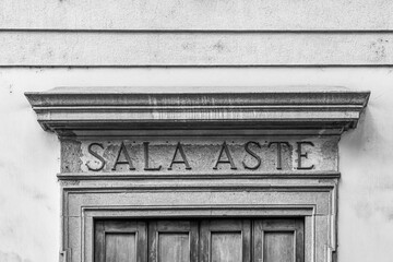 Black and white. Detail of the exterior of an old auction shop, with a sign that says 