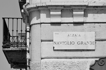 Black and white. Sign of Alzaia Naviglio Grande, the road along the left bank of the Naviglio Grande waterway, on the facade of an old building, Milan, Lombardy, Italy