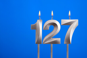 Birthday number 127 - Candle lit on blue background