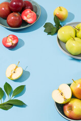 Red, green and yellow apples are arranged on plates on a blue background. Summer or autumn fruits, tasty and healthy snack. Table setting