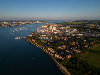 Marchwood waterfront residential area and Power Station at industrial estate. Aerial view of Southampton harbor and the city at distance. Sailing boats mooring. Calm summer day with beautiful sunset.