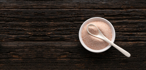 Fine Himalayan pink salt crystals in bowl and spoon - Rustic wooden background