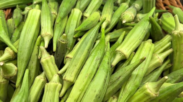 Fresh okra piled in a wicker basket at a market.