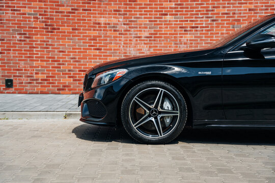 Photo of a black Mercedes C-Class W205 AMG C43. They show details of the car from the outside. Rims, emblems, headlights, lamps in a sporty style. The model stands in a loft style.