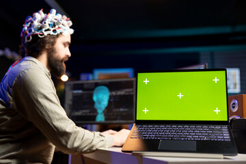 Focus on green screen laptop used by programmer using EEG headset to upload mind into PC. Close up...