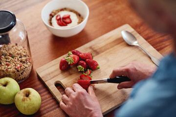 Hands, knife and strawberry with person in kitchen of home from above for diet, health or nutrition. Cooking, food and fruit salad with chef in apartment to prepare meal for detox or wellness