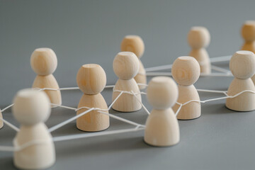 Obraz premium Wooden figures connected by lines, representing the concept of network and social interaction. People connecting in an office or business setting.