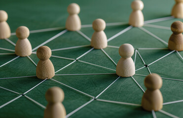 Wooden figures connected by lines, representing the concept of network and social interaction. People connecting in an office or business setting.