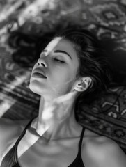 A woman in silhouette, lying down, eyes closed, enjoying tranquil solitude with the sun setting behind her.