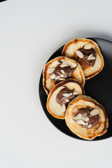 Plate of pancakes dripping with Nutella and almond crumbs with dark gray background.. Copy space for text. Mockup for menu, Pancake day