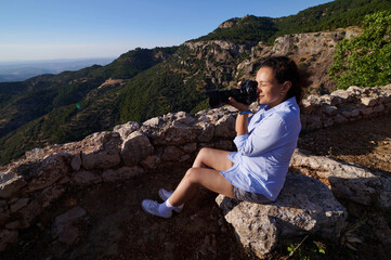 Naklejka premium Woman photographing scenic mountain landscape in the summer with professional camera