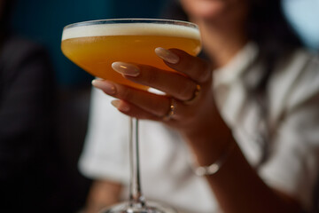 Bartender pours pink cocktail into martini glass with flair