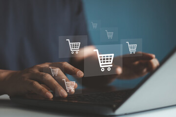 Young man hands typing on keyboard of laptop computer with shopping cart icon virtual screen. Online shopping, Online payment and e-commerce concept. Business financial technology.