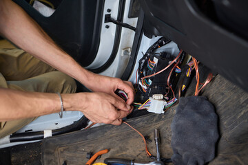 Closeup image featuring hands fixing electrical wires in a car for maintenance and repair