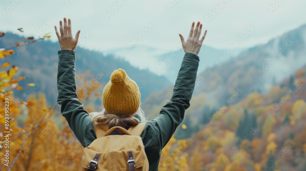 Canvas Prints A woman wearing a yellow hat and a green jacket is standing on a mountain top