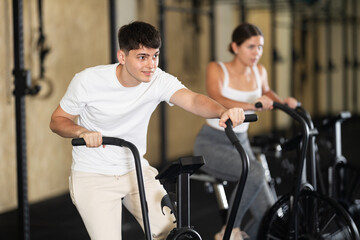 Young athletic man working out on exercise bike in gym