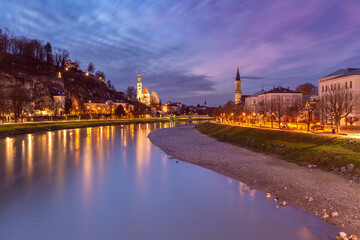 Obraz premium Salzburg at dusk with illuminated buildings and Salzach River, Austria